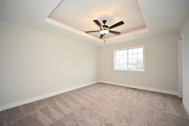 carpeted empty room with a tray ceiling, ornamental molding, and ceiling fan