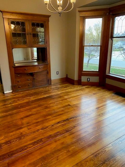 unfurnished dining area with hardwood / wood-style floors and an inviting chandelier