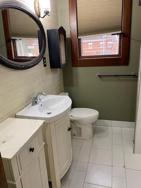 bathroom with tile patterned floors, wood walls, vanity, and toilet