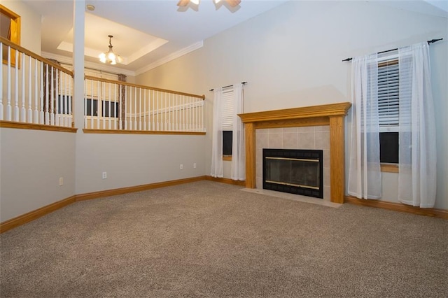 unfurnished living room featuring carpet flooring, an inviting chandelier, a towering ceiling, a tiled fireplace, and ornamental molding