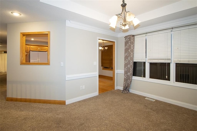 carpeted spare room featuring ornamental molding and a notable chandelier