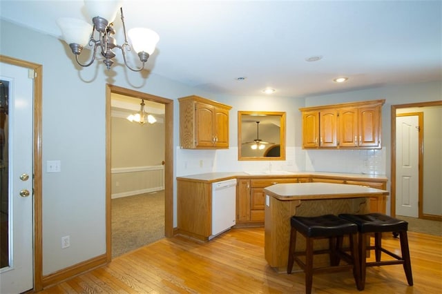 kitchen featuring a breakfast bar, a center island, white dishwasher, light hardwood / wood-style floors, and a chandelier