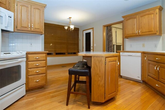 kitchen with hanging light fixtures, light hardwood / wood-style flooring, a notable chandelier, white appliances, and a kitchen island