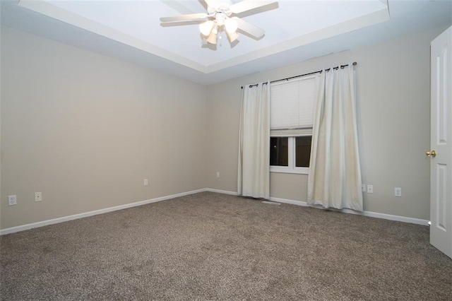 carpeted empty room featuring a raised ceiling and ceiling fan