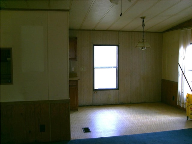 carpeted spare room with ceiling fan and wood walls