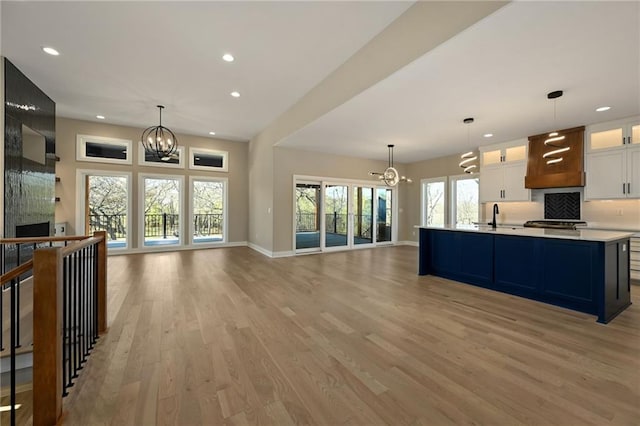 kitchen featuring white cabinets, light wood-type flooring, decorative light fixtures, and a fireplace