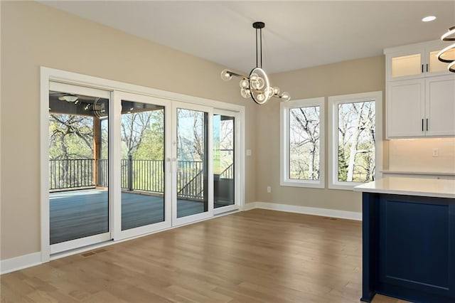 unfurnished dining area featuring a wealth of natural light, dark hardwood / wood-style flooring, and a notable chandelier