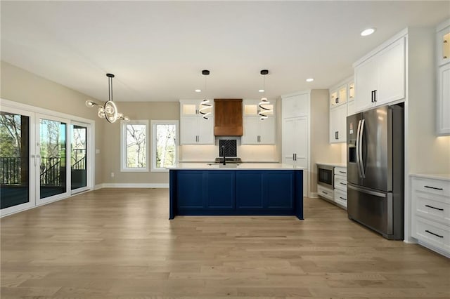 kitchen featuring white cabinets, appliances with stainless steel finishes, and decorative light fixtures