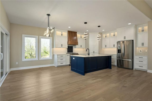 kitchen with a kitchen island with sink, white cabinetry, premium range hood, and appliances with stainless steel finishes