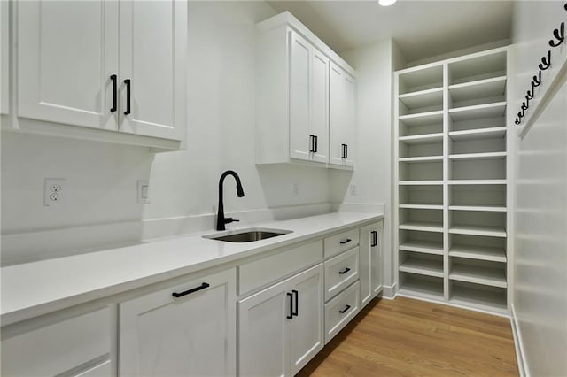 bar featuring white cabinetry, sink, and light hardwood / wood-style flooring