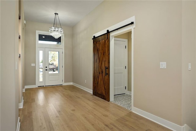 entrance foyer featuring a barn door, light hardwood / wood-style flooring, and a notable chandelier