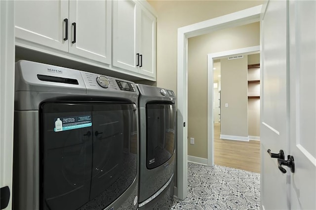 laundry room featuring cabinets, separate washer and dryer, and light wood-type flooring