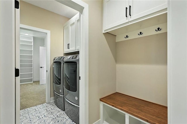 washroom featuring washing machine and dryer, light carpet, and cabinets