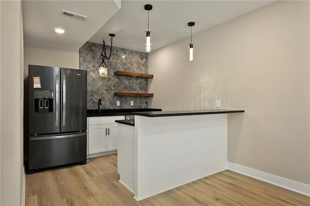 kitchen featuring white cabinetry, light hardwood / wood-style flooring, pendant lighting, and stainless steel refrigerator with ice dispenser