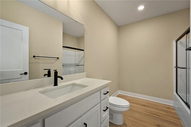 full bathroom featuring vanity, hardwood / wood-style flooring, toilet, and bath / shower combo with glass door