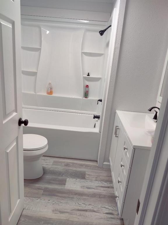 full bathroom with shower / tub combination, toilet, vanity, and hardwood / wood-style flooring