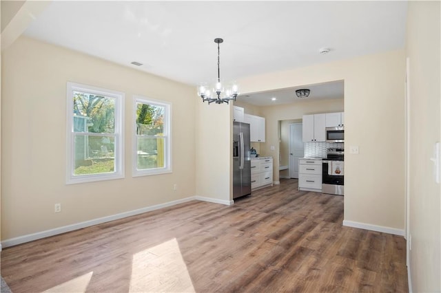 kitchen with white cabinetry, backsplash, pendant lighting, light hardwood / wood-style floors, and appliances with stainless steel finishes