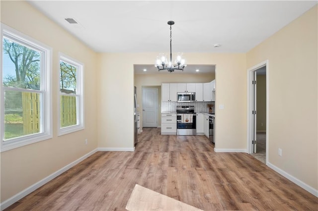 kitchen featuring backsplash, stainless steel appliances, decorative light fixtures, light hardwood / wood-style floors, and white cabinetry