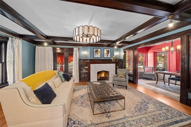 living area with beamed ceiling, coffered ceiling, and wood finished floors