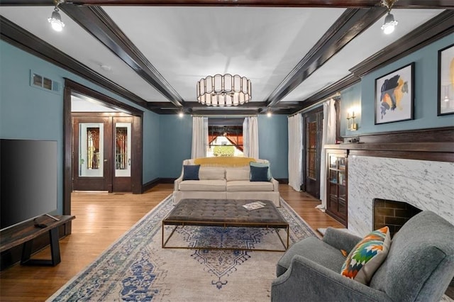 living area featuring beam ceiling, visible vents, wood finished floors, and ornamental molding