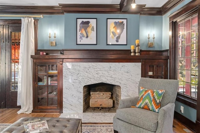 living area featuring crown molding, wood finished floors, and a high end fireplace