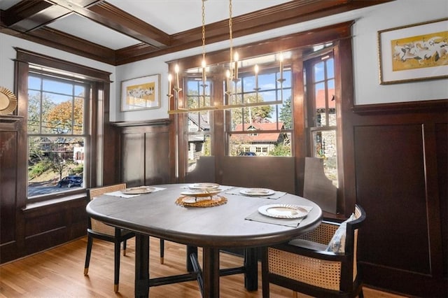 dining room with coffered ceiling, a wainscoted wall, beamed ceiling, light wood-type flooring, and a decorative wall