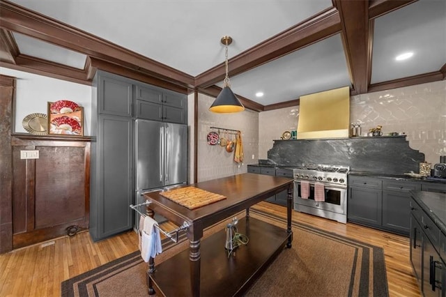 kitchen featuring gray cabinetry, appliances with stainless steel finishes, wall chimney exhaust hood, dark countertops, and decorative light fixtures