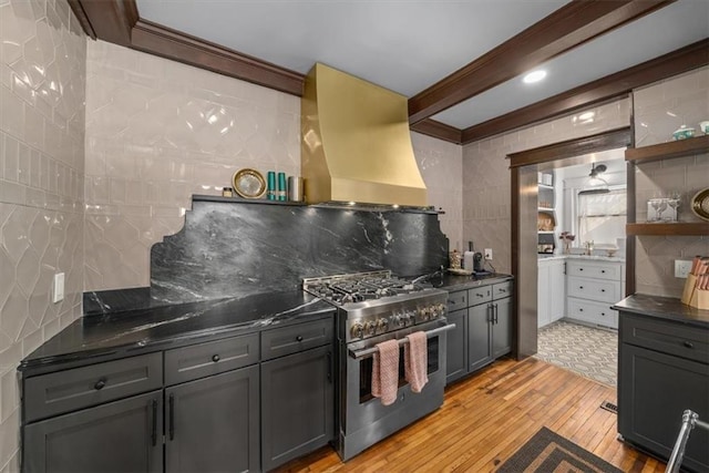 kitchen with extractor fan, gray cabinetry, open shelves, stainless steel range, and dark countertops