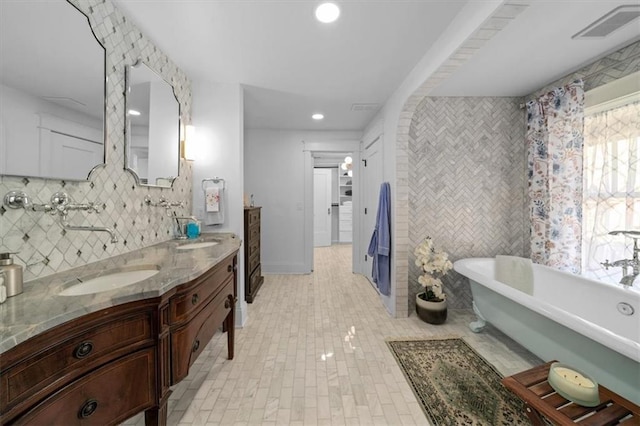 full bathroom featuring recessed lighting, a sink, visible vents, a soaking tub, and double vanity