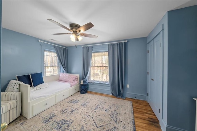 bedroom featuring baseboards, multiple windows, visible vents, and wood finished floors