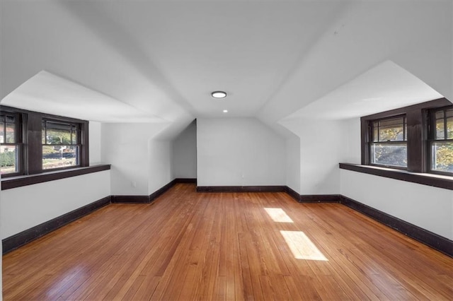 additional living space with lofted ceiling, wood finished floors, and baseboards