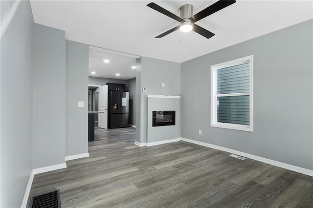 unfurnished living room featuring ceiling fan and dark hardwood / wood-style floors