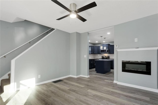 unfurnished living room featuring hardwood / wood-style floors and ceiling fan