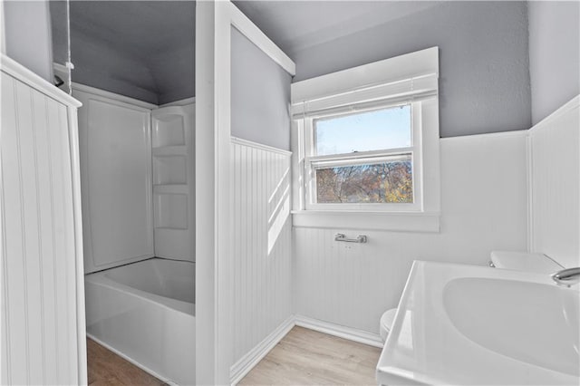 bathroom with wood-type flooring,  shower combination, and toilet