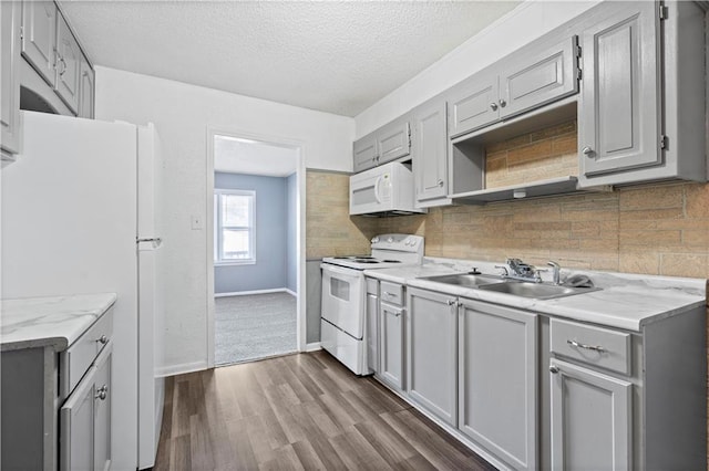 kitchen featuring white appliances, sink, dark hardwood / wood-style floors, decorative backsplash, and a textured ceiling