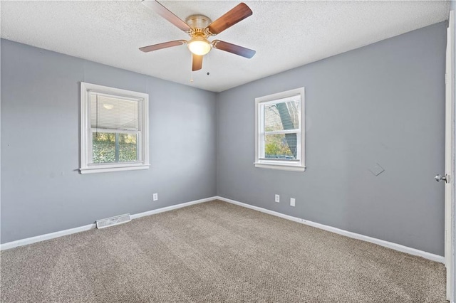 carpeted empty room featuring a wealth of natural light, ceiling fan, and a textured ceiling