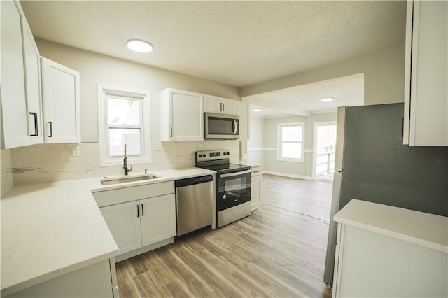 kitchen featuring white cabinets, appliances with stainless steel finishes, backsplash, and sink