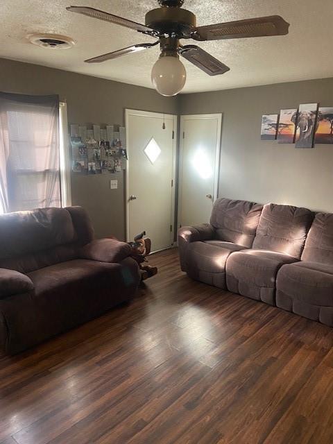 living room with ceiling fan, dark wood-type flooring, and a textured ceiling