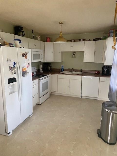 kitchen featuring white cabinets, white appliances, sink, and hanging light fixtures