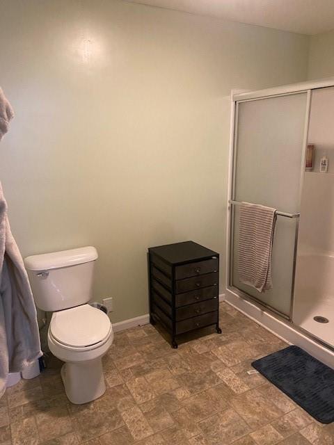 bathroom with a shower with door and toilet