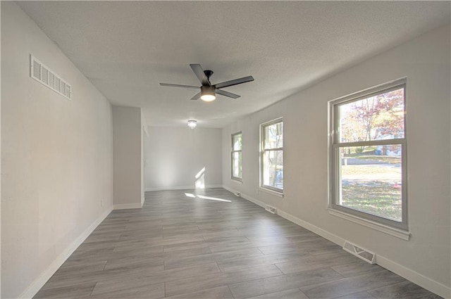 spare room with ceiling fan, light hardwood / wood-style floors, and a textured ceiling