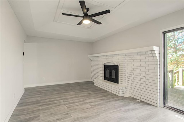 unfurnished living room featuring hardwood / wood-style floors, ceiling fan, and a brick fireplace