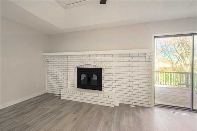 unfurnished living room featuring wood-type flooring and a brick fireplace