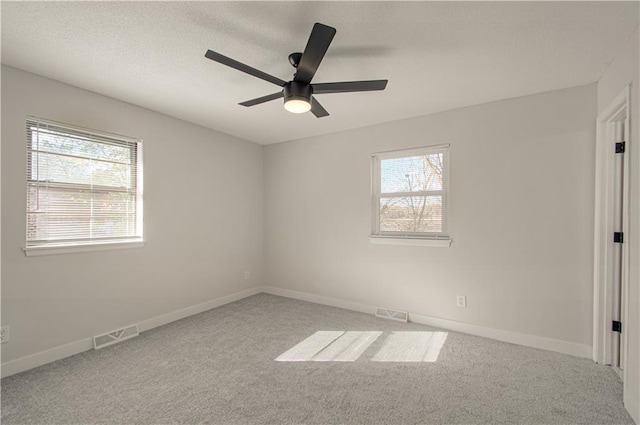 carpeted empty room featuring ceiling fan and a healthy amount of sunlight