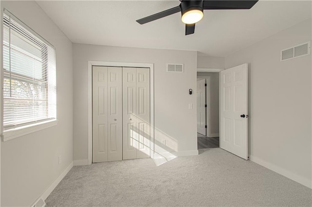 unfurnished bedroom featuring ceiling fan, light carpet, and a closet