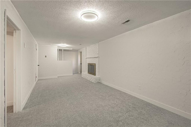 unfurnished living room featuring carpet flooring, a textured ceiling, and a brick fireplace