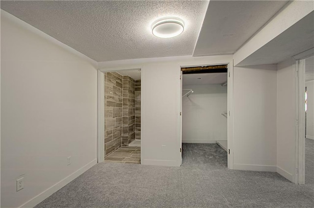 unfurnished bedroom with ensuite bath, a textured ceiling, light colored carpet, a spacious closet, and a closet