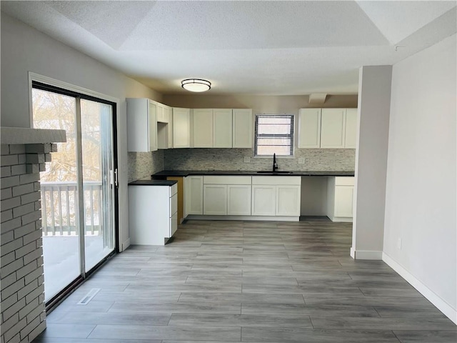 kitchen with tasteful backsplash, sink, white cabinets, and lofted ceiling