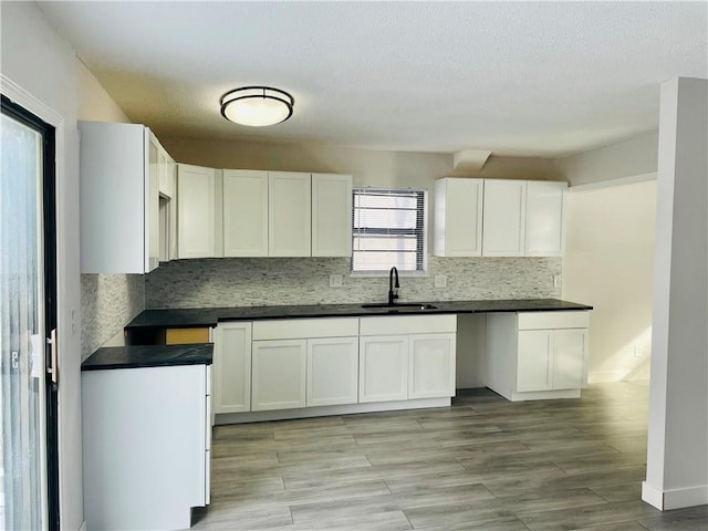 kitchen featuring white cabinets, decorative backsplash, light hardwood / wood-style floors, and sink