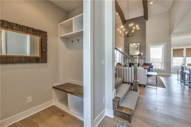 mudroom with an inviting chandelier, beam ceiling, baseboards, and wood finished floors